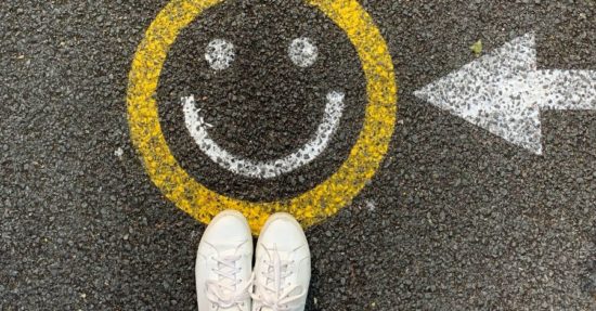 Smiley face drawn on pavement with an arrow pointing to it