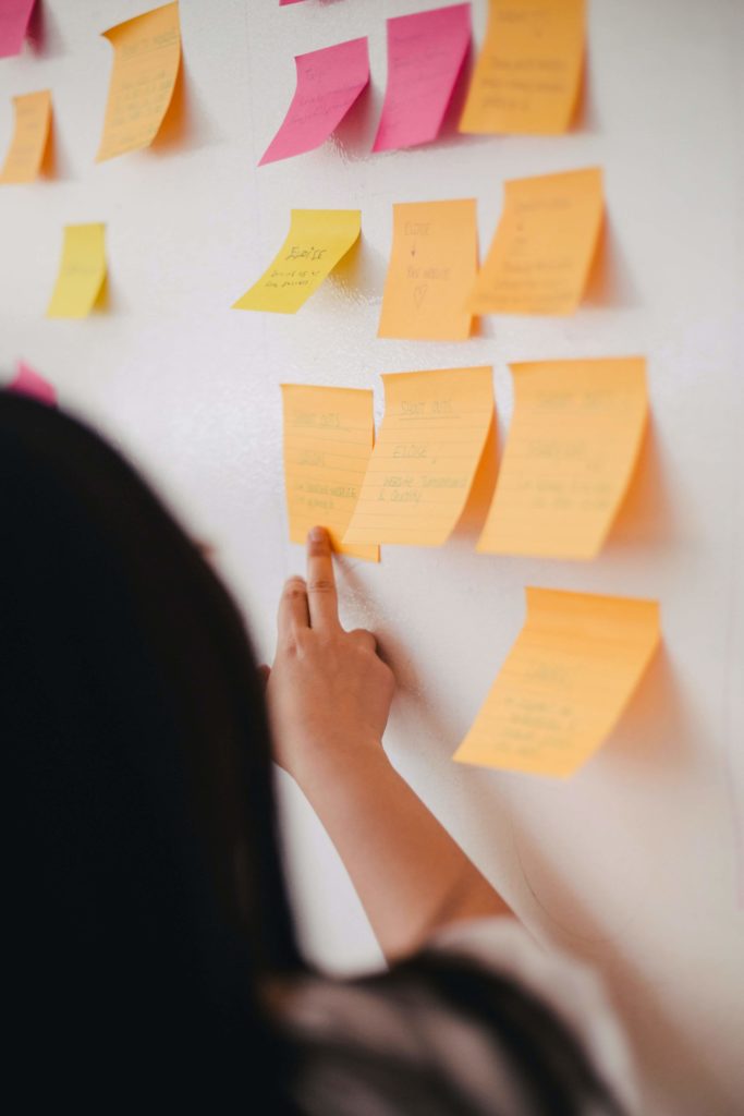 Woman pointing at a wall of sticky notes